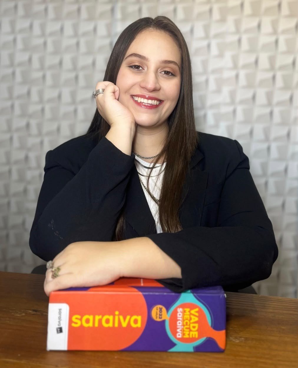 Dra. Sara Gabelini em seu escritório, apoiada sobre livros jurídicos